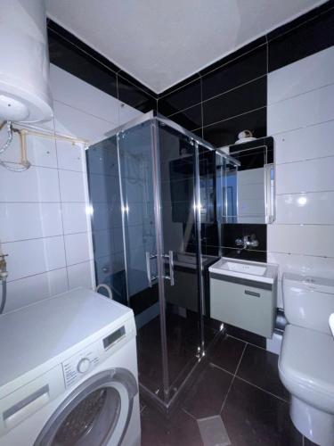 a bathroom with a washing machine and a toilet at Bleon Apartment in Prizren