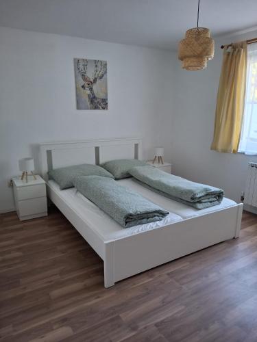 a white bed in a white bedroom with wooden floors at Ferienwohnung Edith-Maria in Bad Goisern