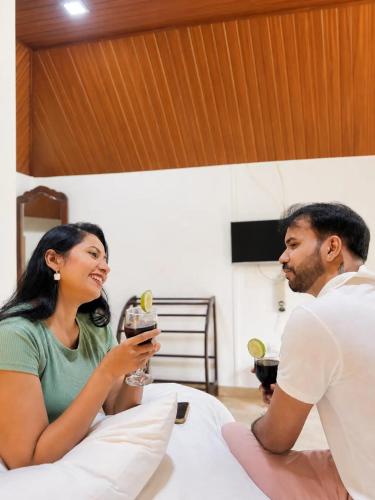a man and a woman sitting in bed with a drink at Vegas Nature Resort in Dankotuwa