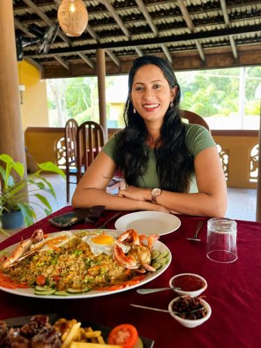 a woman sitting at a table with a plate of food at Vegas Nature Resort in Dankotuwa