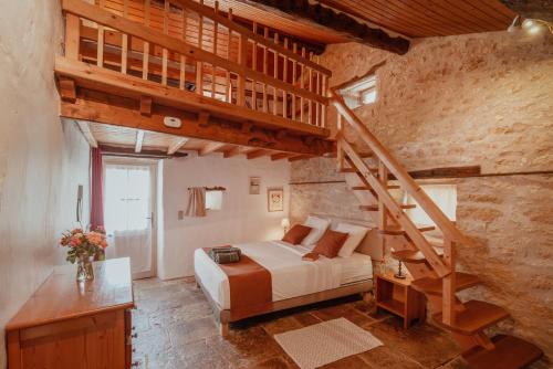 a bedroom with a bed and a wooden staircase at Les instants du lot in Trespoux-Rassiels