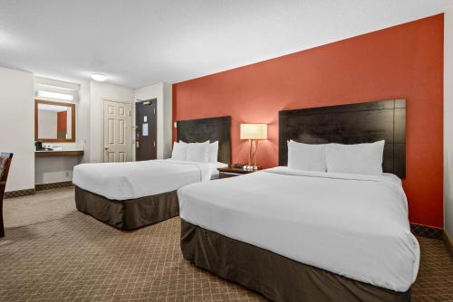 two beds in a hotel room with red walls at Comfort Inn & Suites Airport South in Calgary