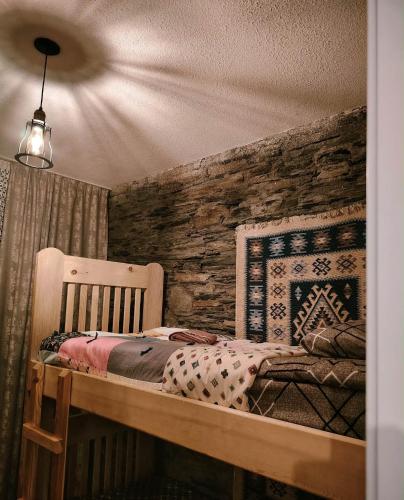 a bedroom with a bed and a stone wall at Nanila in Ushguli