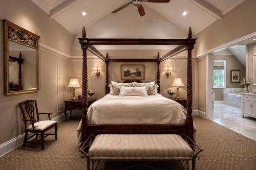 a bedroom with a canopy bed and a chair at The Federal Pointe Inn Gettysburg, an Ascend Collection Hotel in Gettysburg