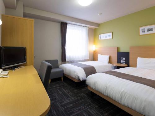 a hotel room with two beds and a desk at Comfort Hotel Tsubamesanjo in Sanjo