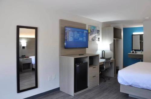 a hotel room with a bed and a mirror at Clarion Inn in Greenville