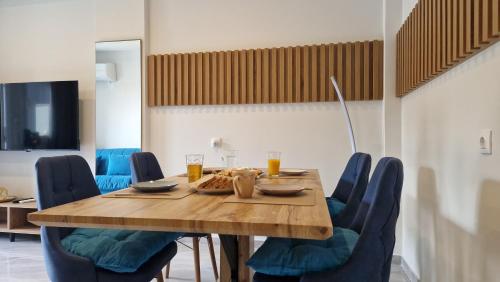 a dining room table with blue chairs and orange juice at Milaluxe in Paralia Katerinis