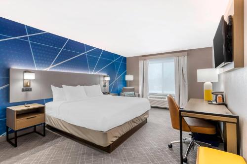 a hotel room with a large bed and a desk at Comfort Inn & Suites in Watervliet