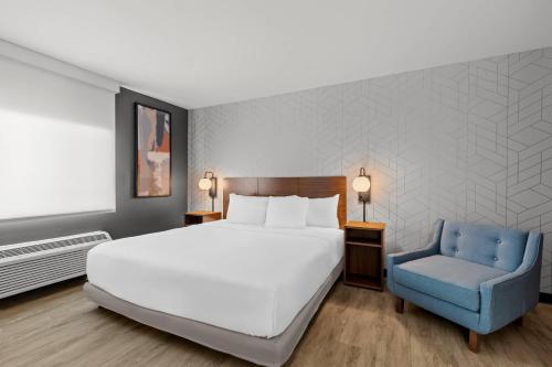a bedroom with a bed and a blue chair at Everhome Suites Temecula Wine Country in Temecula