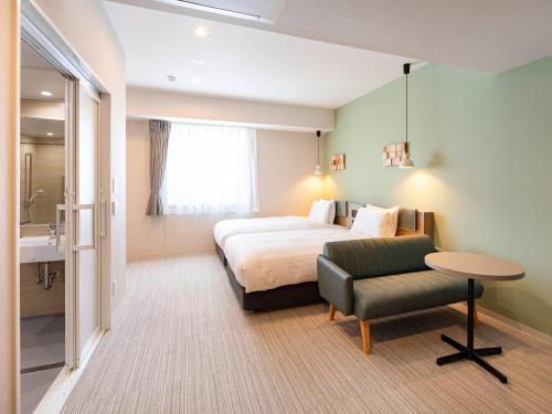 a bedroom with a bed and a table and a chair at Comfort Hotel Chitose in Chitose