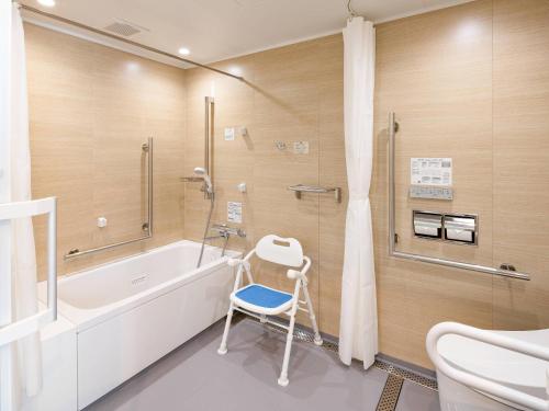 a bathroom with a tub and a chair next to a shower at Comfort Hotel Chitose in Chitose