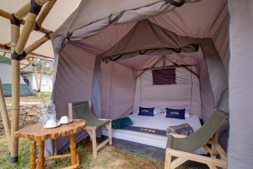 a bed in a tent with a table and chairs at Kampoeng Regang By BHATARA in Patengan