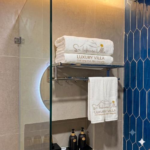 a bathroom with a shower with towels on a shelf at Su House Villa in Gò Ba Quần