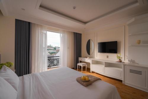 a bedroom with a bed with a desk and a television at Nature Hotel - Pham Hong Thai in Da Lat