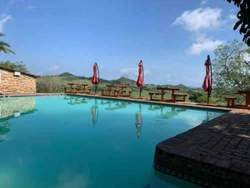 a swimming pool with tables and umbrellas at Klipspringer Lodge in Nelspruit
