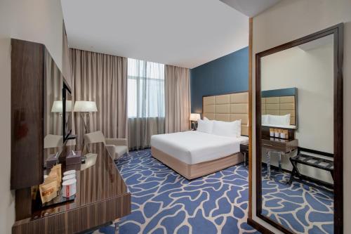 a hotel room with a bed and a mirror at Ramada Abu Dhabi Corniche in Abu Dhabi