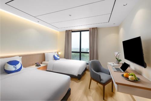 a hotel room with two beds and a desk and a tv at FOX Lite Hotel Majalaya in Bojong