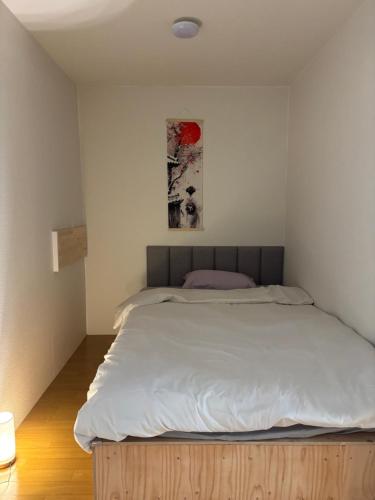 a bedroom with a large bed with white sheets at さくらやゲストハウス in Tokushima