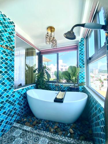 a bathroom with a tub with blue tiles and a window at Athena Hotel Quy Nhơn in Quy Nhon