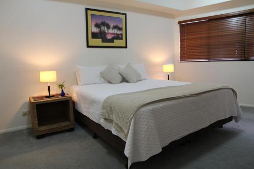 a bedroom with a large bed and two lamps at Darwin Deluxe Apartments in Darwin
