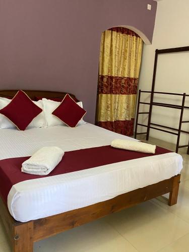 a bed with red and white pillows in a room at French Garden Eagle Wings Inn in Trincomalee