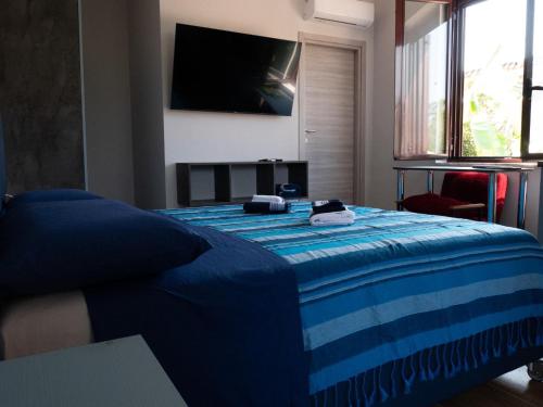 a bedroom with a blue bed with a television on the wall at Antiche Torri Guest House in Castel Volturno