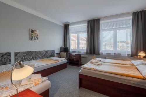 two beds in a room with two windows at Hotel Morava Jevíčko in Jevíčko