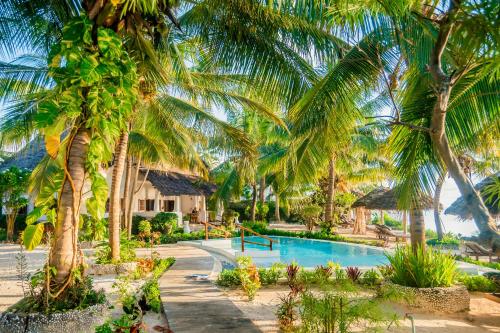 a resort with a swimming pool and palm trees at Villa Juliana in Jambiani