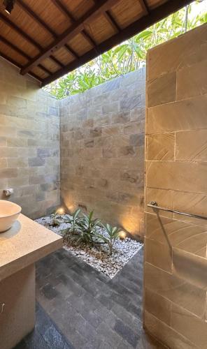 a bathroom with a shower with a stone wall at The Haven in Gili Trawangan