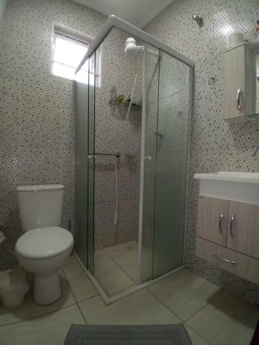 a bathroom with a toilet and a glass shower at Quarto Casal Cinza in Artur Nogueira