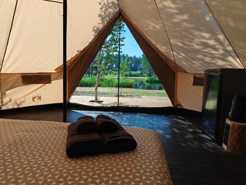 a pair of slippers sitting on a bed in a tent at AVOTUPJI GLEMPING telts in Allaži