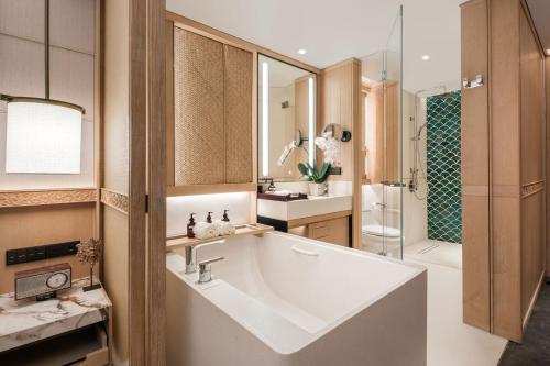 a bathroom with a large white sink and a tub at Bali Mandira Beach Resort & Spa in Legian