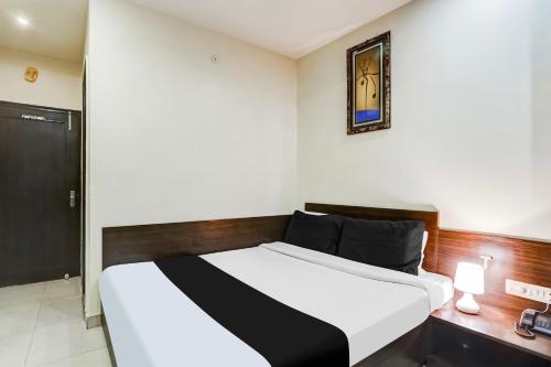 a bedroom with a white bed with a wooden headboard at Super Collection O Sindhi Camp Formerly Hotel Abhinandan Inn in Jaipur