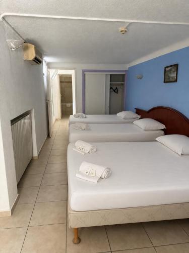 a row of four beds in a room at Hôtel Le Robinson in Beaucaire