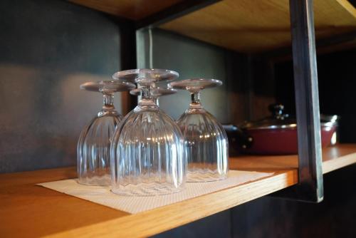 three wine glasses sitting on top of a shelf at Beringei house Kujukuri in Katakai
