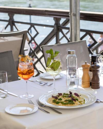 a table with a plate of food and glasses on it at Riverside Hotel Merian - opening 2026 in Basel