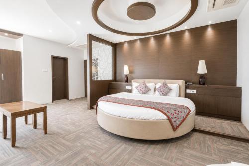 a hotel room with a large bed and a table at Viz Park Hotel - Business Hotel & Banquet, GIDC Anand in Anand