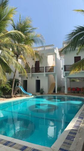 a pool in front of a house with palm trees at Jannataan Hotel in Lamu