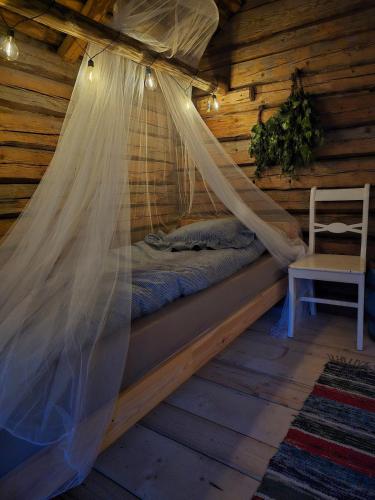 a bed in a log cabin with a mosquito net at Stockboden Kvarken Off Grid Cabin No Electricity or Running Water in Oravais