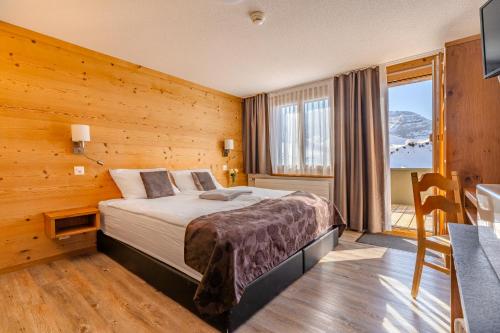 a bedroom with a bed and a table and a window at Berghotel Hahnenmoos in Adelboden