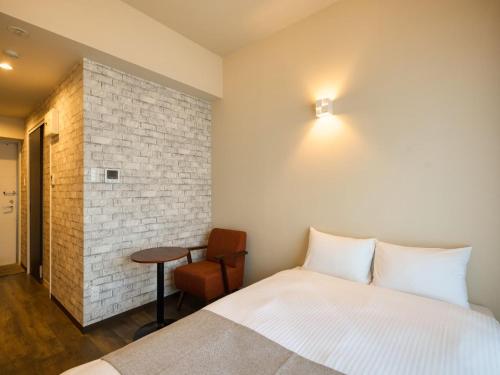 a bedroom with a bed and a table and a chair at New Normal Hotel in ASAHIBASHIEKI in Naha