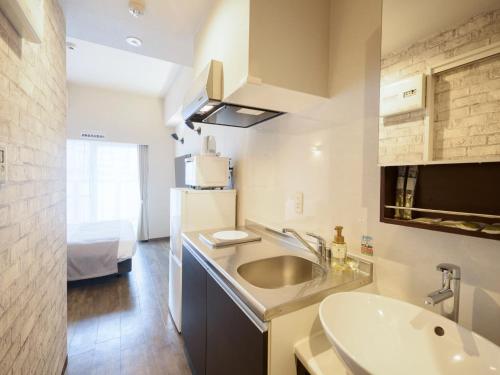 a small bathroom with a sink and a sink at New Normal Hotel in ASAHIBASHIEKI in Naha