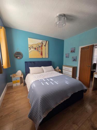 a bedroom with a bed with a blue wall at The Hyding Place on George Street in Whitby
