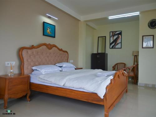 a bedroom with a wooden bed with white sheets and pillows at Genesis villa in Guwahati