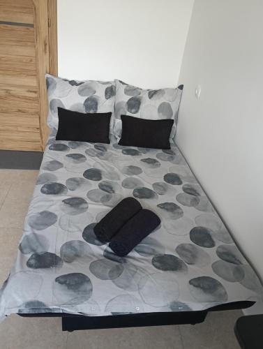a bed with black pillows and a gray and gray blanket at Zadar Sunhouse Studio with Terrace in Zadar