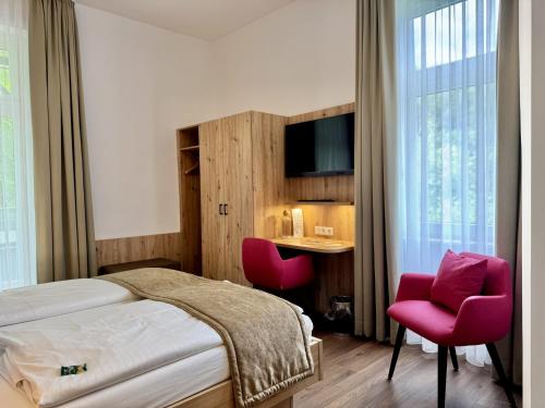 a bedroom with a bed and two red chairs at Solehotel Winterberg in Bad Harzburg