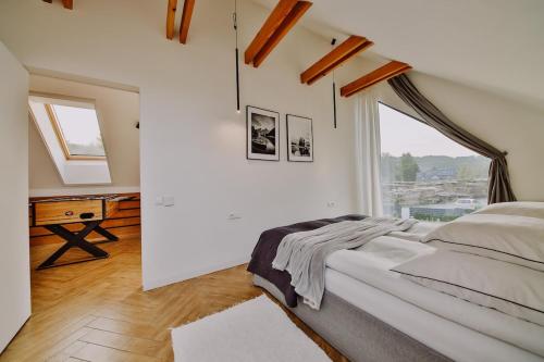 a white bedroom with a large bed and a window at Loftowe Zacisze in Bystra