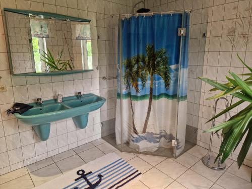 a bathroom with a sink and a shower with a palm tree at Hennickes Fewo in Friedrichshof