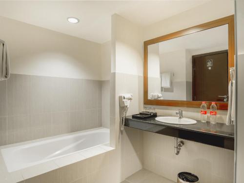 a bathroom with a sink and a mirror at Noormans Hotel Semarang in Semarang