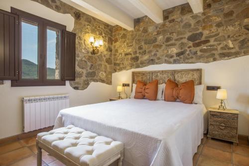 a bedroom with a bed and a stone wall at Cal Potret in Argençola